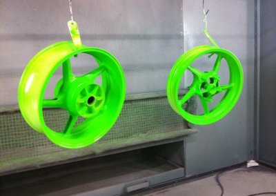 Neon green mag wheels left to hang dry after painting session at Tallaght Powder Coating Ltd.