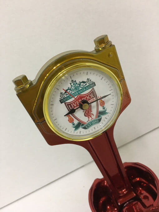 A close-up of a desk clock crafted from a silver Jaguar piston.