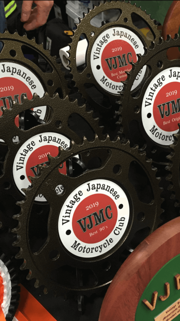 Upcycled motorcycle sprocket clock with a red finish, featuring a black clock face and hands, with a Manchester United logo at the centre
