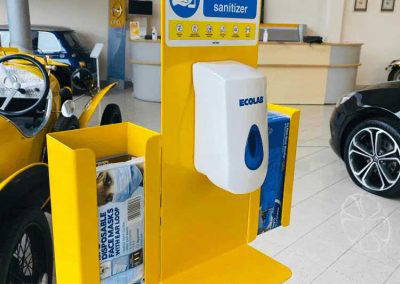 Yellow powder coated hand sanitiser stand with dispenser and side brochure holders in office showroom